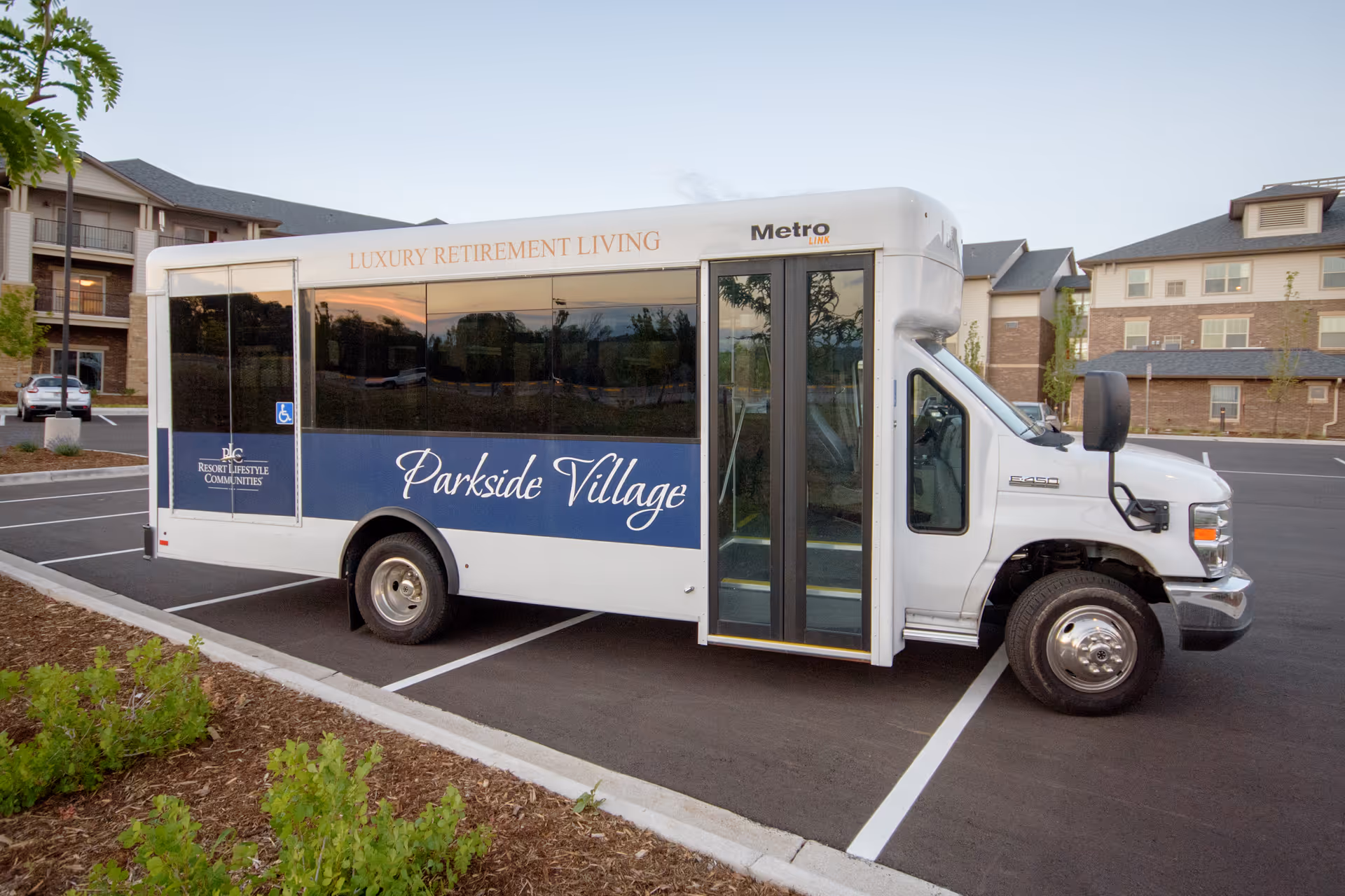 A white shuttle bus labeled "Parkside Village" parked in front of a retirement community building.