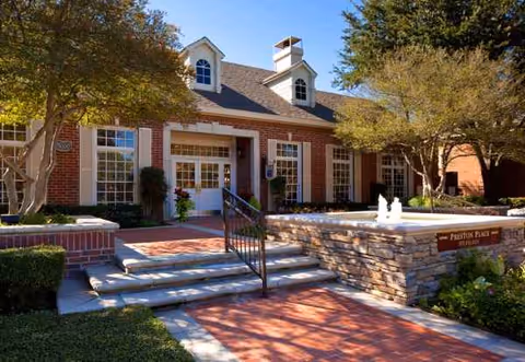 Exterior view of Preston Place senior living facility: brick building with steps, ramp, and a fountain.