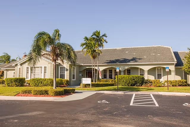 Exterior view of Brookdale Tequesta senior living facility with palm trees and accessible parking.