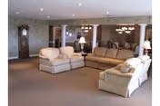 Spacious Wheatland Manor living room featuring beige couches, lamps, and a grandfather clock.
