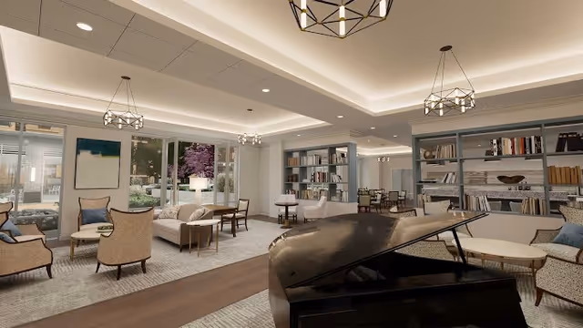 Spacious, well-lit communal lounge with a grand piano, multiple seating areas, bookshelves, and large windows overlooking a garden.