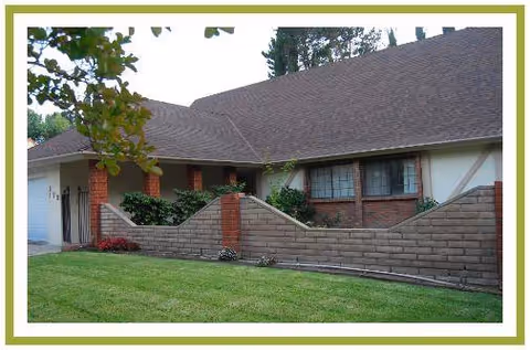 Front exterior of Happy Home Care facility, a single-story building with brick wall and green lawn.
