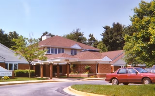 Exterior view of Malta House senior living facility with driveway and parked car