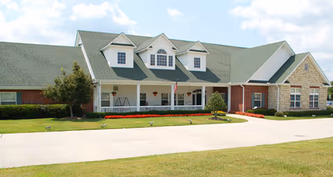 Front exterior of the Navion of Greenville building with a green roof, white porch columns, American flag, and landscaped lawn.