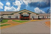 Exterior view of LakePoint Augusta senior living facility with curved driveway and landscaped grounds.
