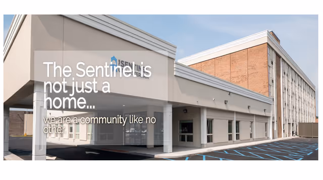 Front entrance of The Sentinel of Amsterdam senior living building with a covered drop-off area and an overlaid slogan.