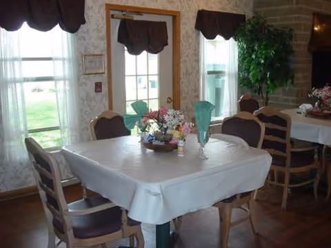A dining room with tables covered by white cloths and floral centerpieces.