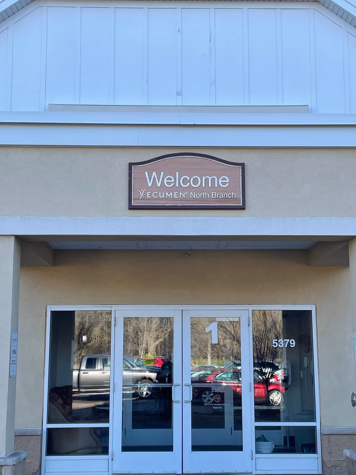Front entrance of Ecumen North Branch with double glass doors and a 'Welcome Ecumen North Branch' sign above.