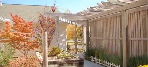 Outdoor garden area at Brookdale Morehead City with a wooden pergola and autumn trees.