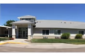 Exterior view of Pioneer Place Assisted Living entrance with blue sky and landscaping.