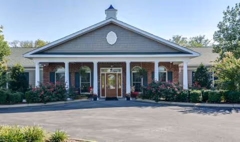 Front view of Hickory Gardens senior living facility with brick columns and landscaped entrance.