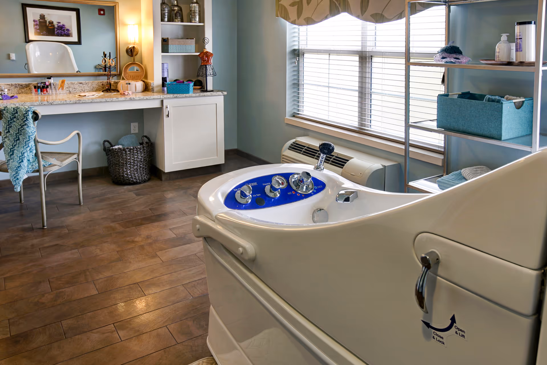 Assisted bathing room with a walk-in tub in the foreground, a vanity and chair to the left, and shelving by a window.