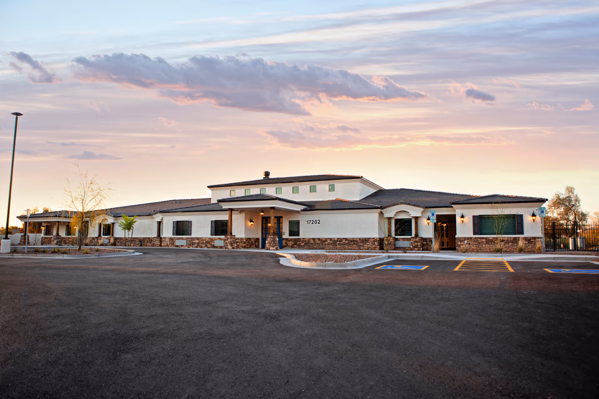 Exterior view of BeeHive Homes Assisted Living building with parking lot at sunset