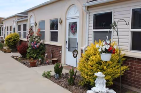 Exterior view of a retirement community with front doors, walkway, and potted plants.