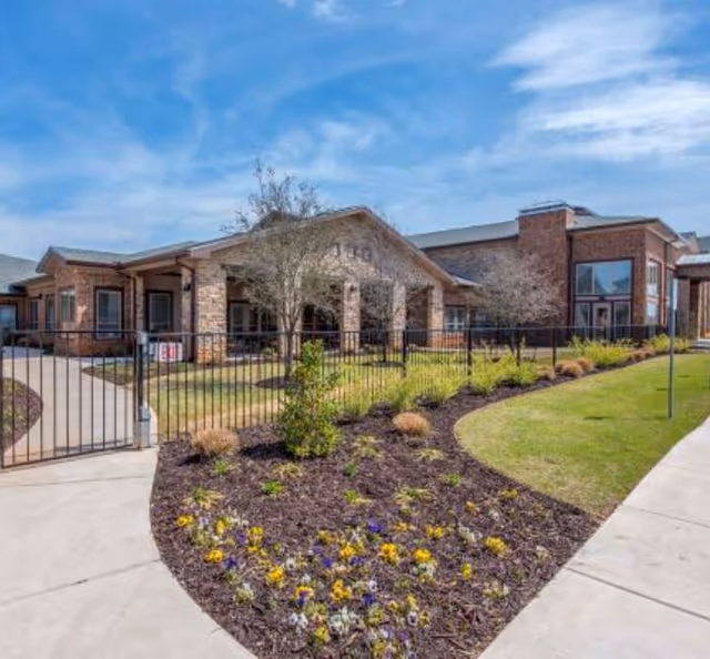 Exterior view of Legend of Edmond senior living campus with brick building and landscaped front yard.