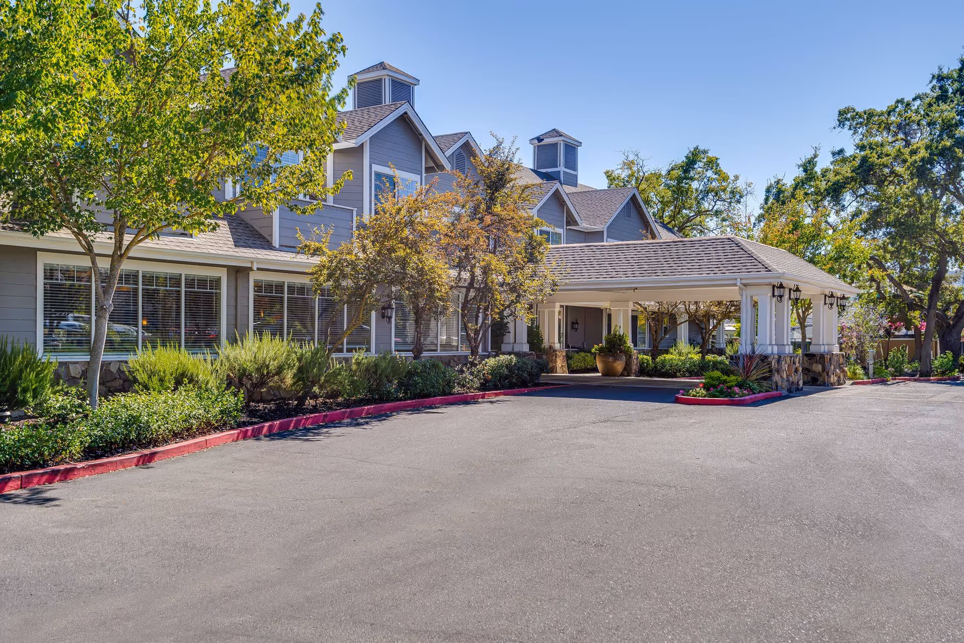 Exterior front entrance of Sunrise of Danville showing a covered porte-cochere, landscaped grounds, and parking area.