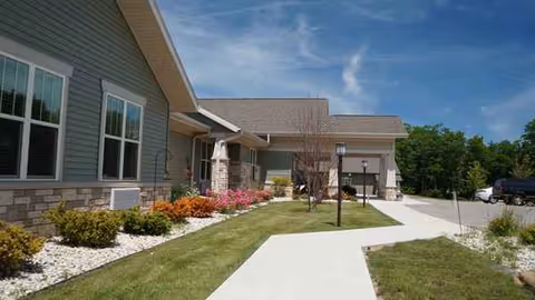 Exterior of a memory care facility with landscaped walkway and parking.