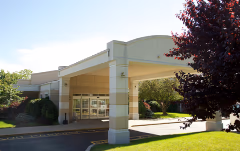 Senior living facility entrance with covered drive-up area and manicured landscaping.
