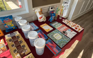 Promotional pamphlets and cups arranged on a burgundy information table by a window.