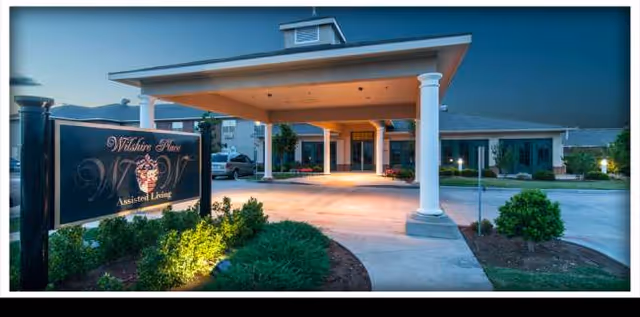 Front exterior of Wilshire Place Assisted Living with a covered entrance and sign.