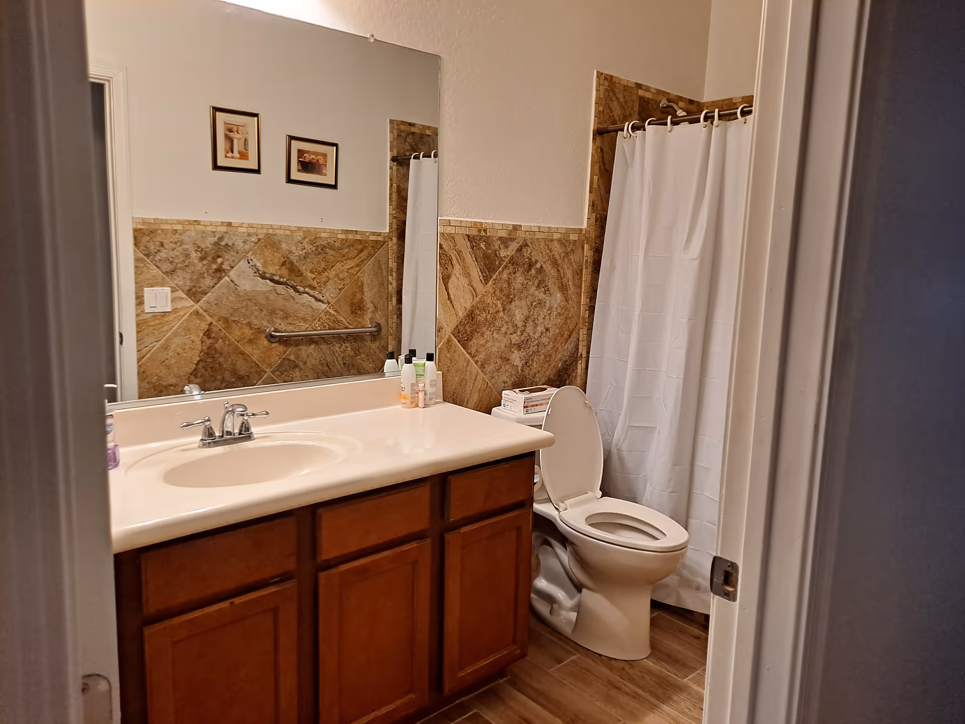 Bathroom in a senior living facility with sink, toilet, and shower curtain.