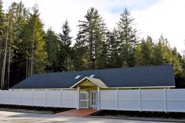 Front view of a single-story memory care facility with a white fence.