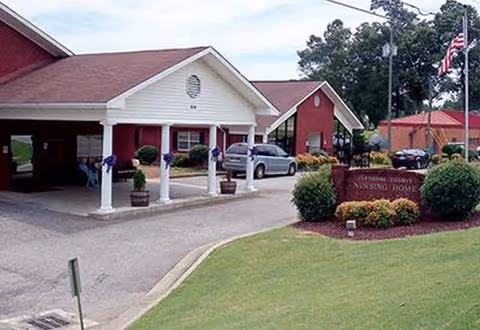 Cleburne County Nursing Home entrance with red buildings, white columns, and manicured lawn.