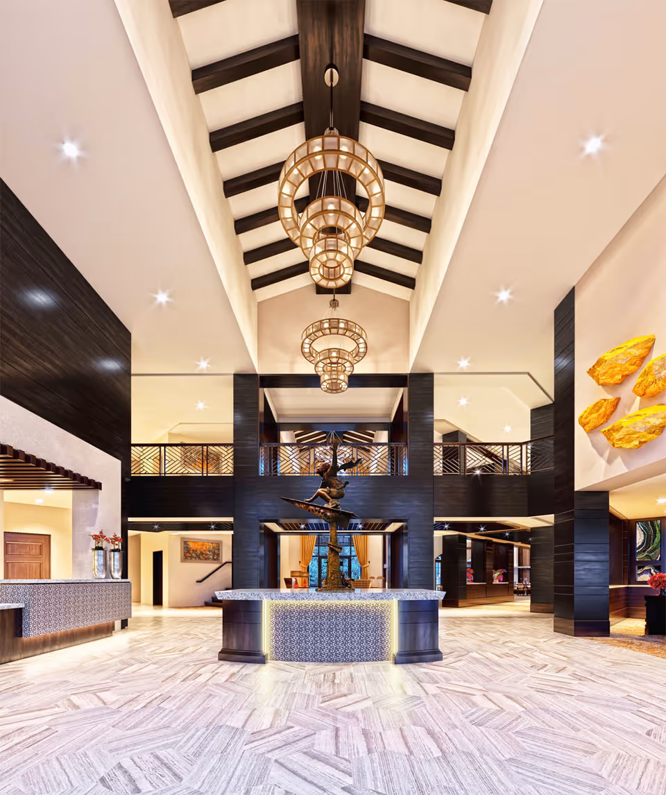 Spacious and elegant senior living facility lobby with high vaulted ceiling featuring exposed dark wooden beams and large circular chandeliers. The floor is light-colored with a herringbone pattern. A central round reception desk with a decorative sculpture on top is illuminated with soft lighting. Dark wood accents and modern decor elements, including yellow wall art, are visible throughout the space.