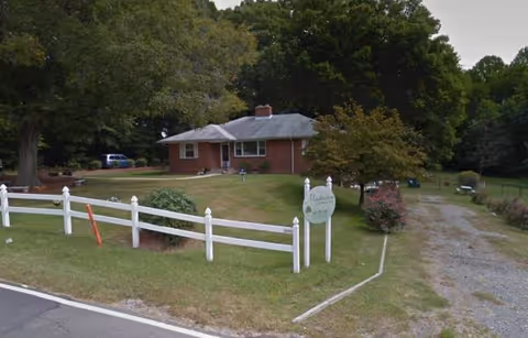 Brick, single-story building with a white fence, trees, and a Meadowview sign in front yard.