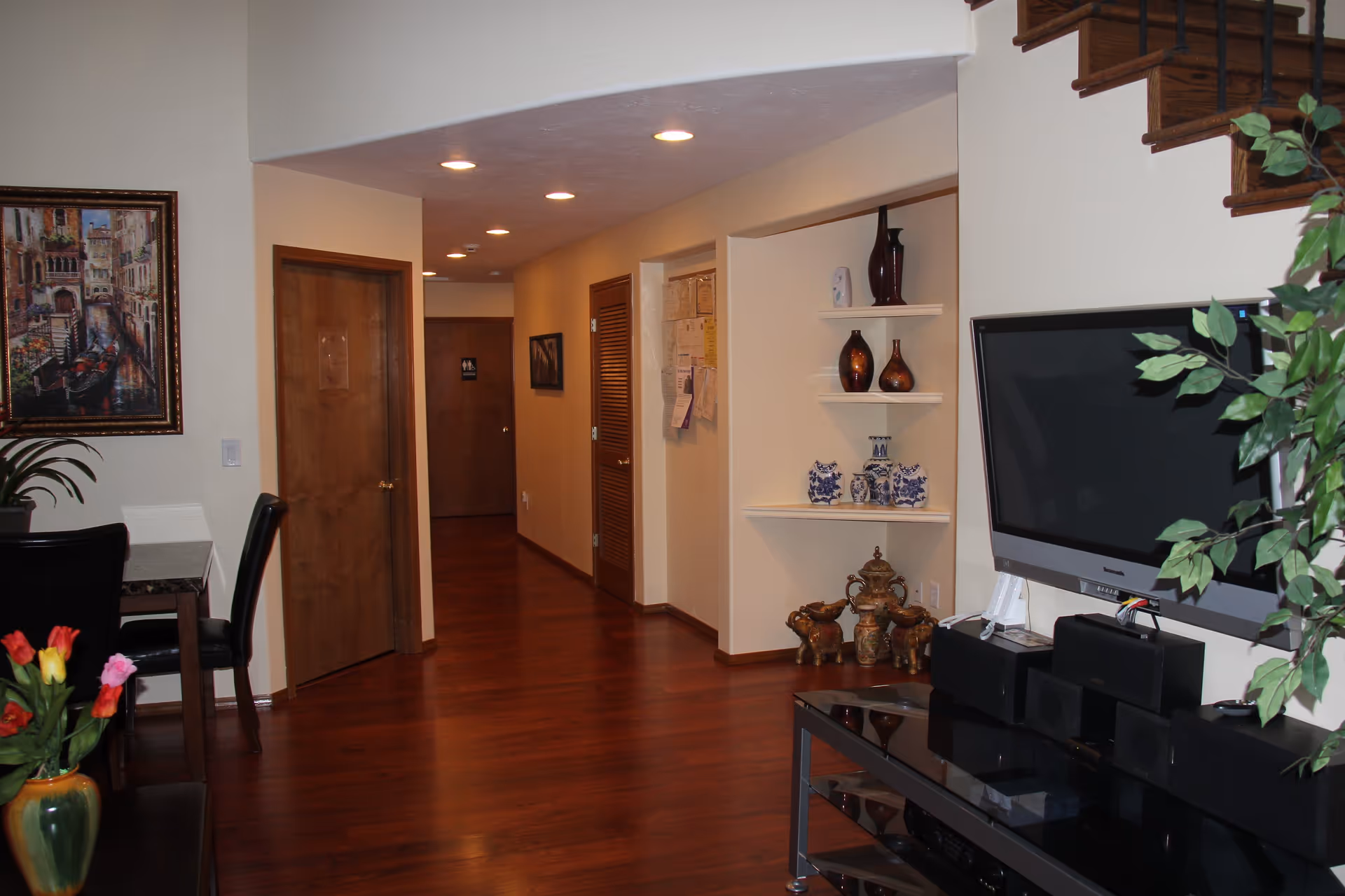 Interior view of Greer's Garden Park with a lobby area featuring wooden flooring, a decorative shelf with vases, and a television set.