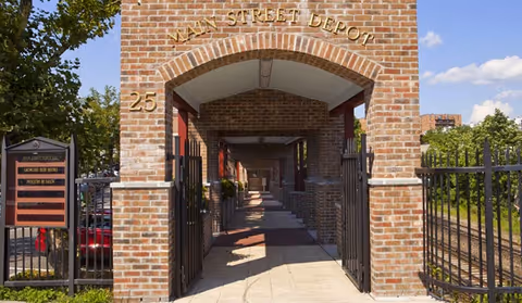 Brick arched entrance labeled "Main Street Depot" with a gated walkway and the number 25 displayed.