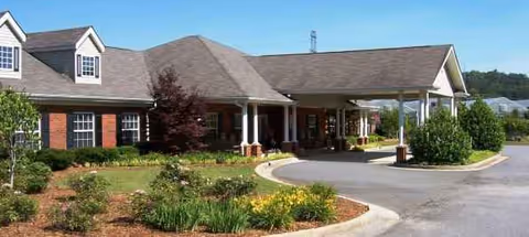 Exterior view of Gaines Park Senior Living front entrance with circular driveway and landscaping.