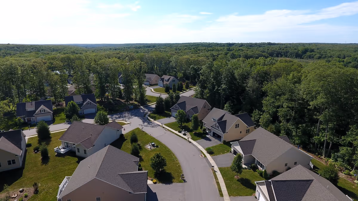 Aerial view of a suburban cul-de-sac with detached homes surrounded by trees and forest.