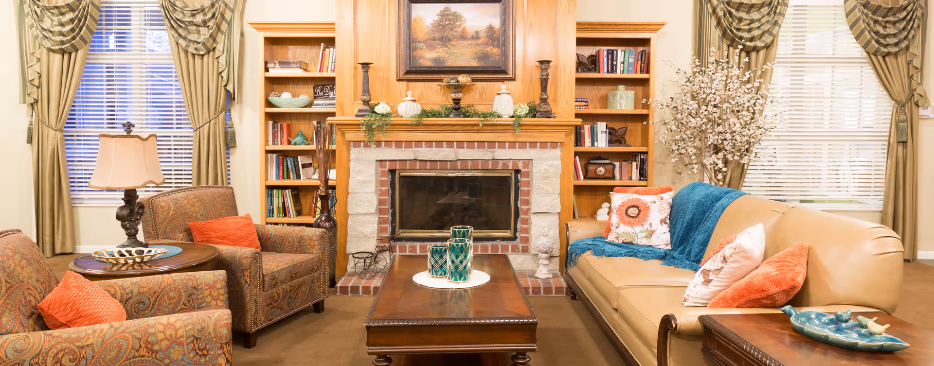 Well-appointed living room with a central brick fireplace flanked by built-in bookshelves, upholstered chairs and a leather sofa around a coffee table.