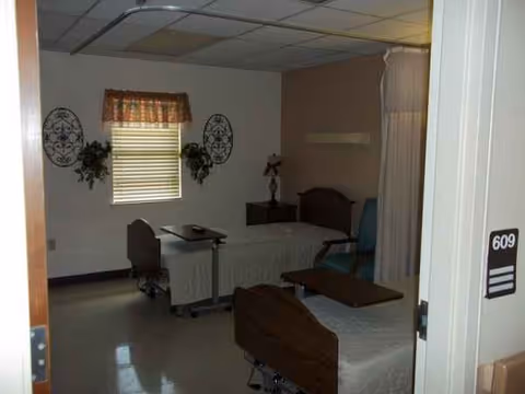 A shared senior living room with two hospital-style beds and a window.