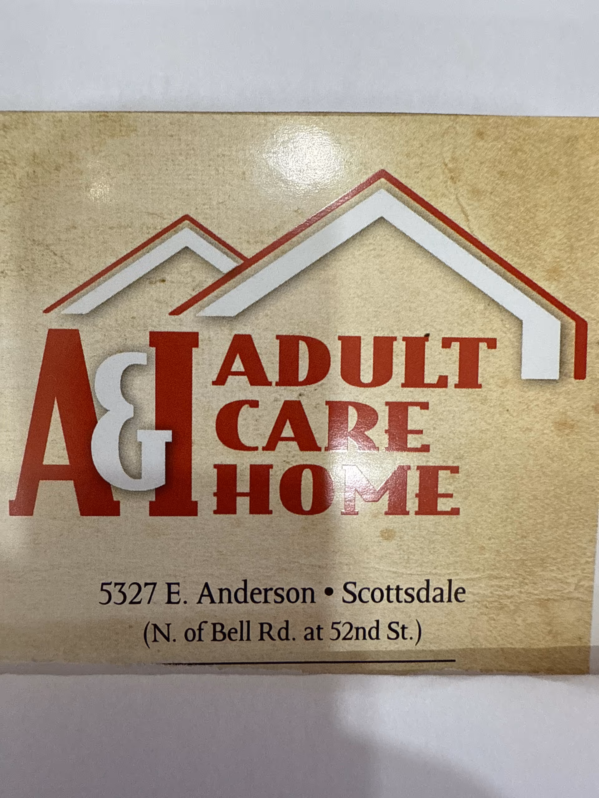 Close-up of a sign that reads 'A & I ADULT CARE HOME' with an address in Scottsdale.