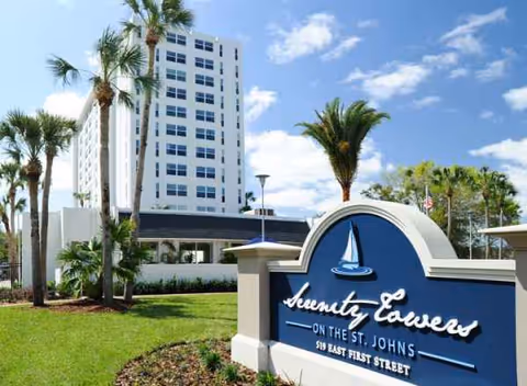 A high-rise senior living building with a curved blue sign reading Serenity Towers on St. Johns.