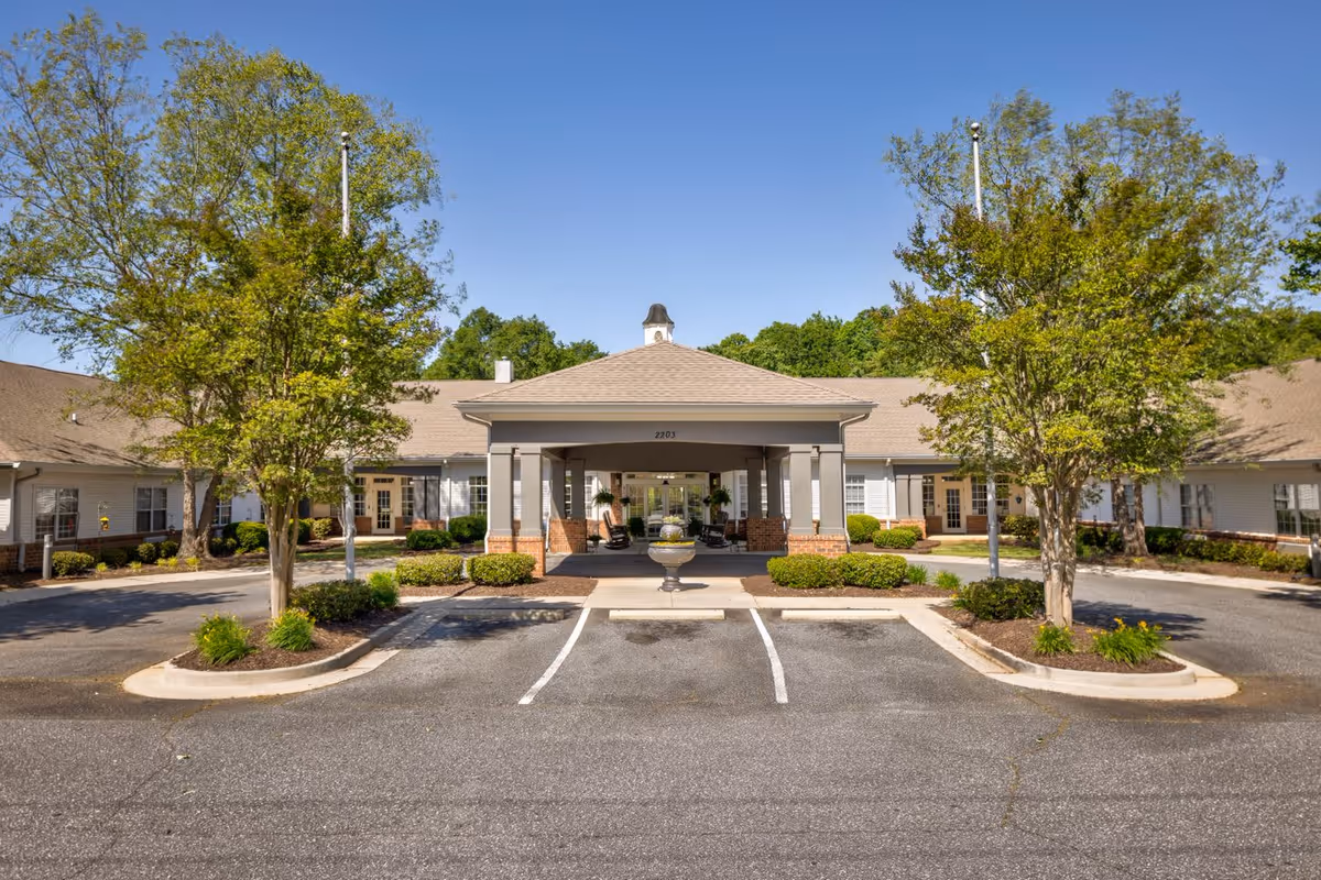 Front exterior view of TerraBella Marchbanks facility showing a single-story building with a covered entrance, surrounded by landscaped greenery and trees under a clear blue sky.