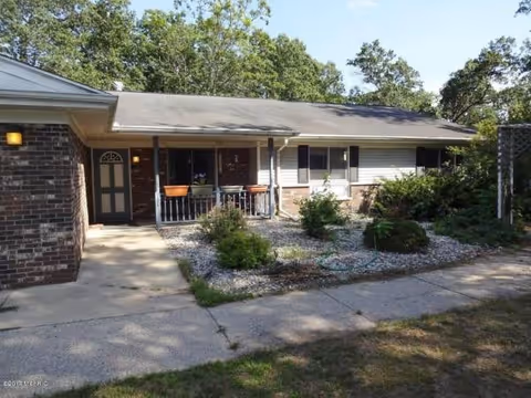 Single-story brick senior living facility front with a covered porch and garden.