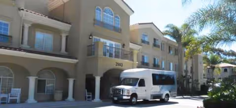 Exterior view of Bayshire Carlsbad facility with a white shuttle bus parked near the entrance.