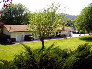 Exterior view of a single-story senior care facility with manicured lawn and trees.