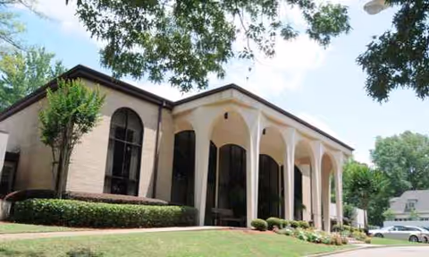 Front exterior view of Lakeland Nursing & Rehab building with arches and surrounding greenery.