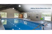 Indoor community swimming pool with lane markers, high vaulted ceiling, windows, and pool ladder.