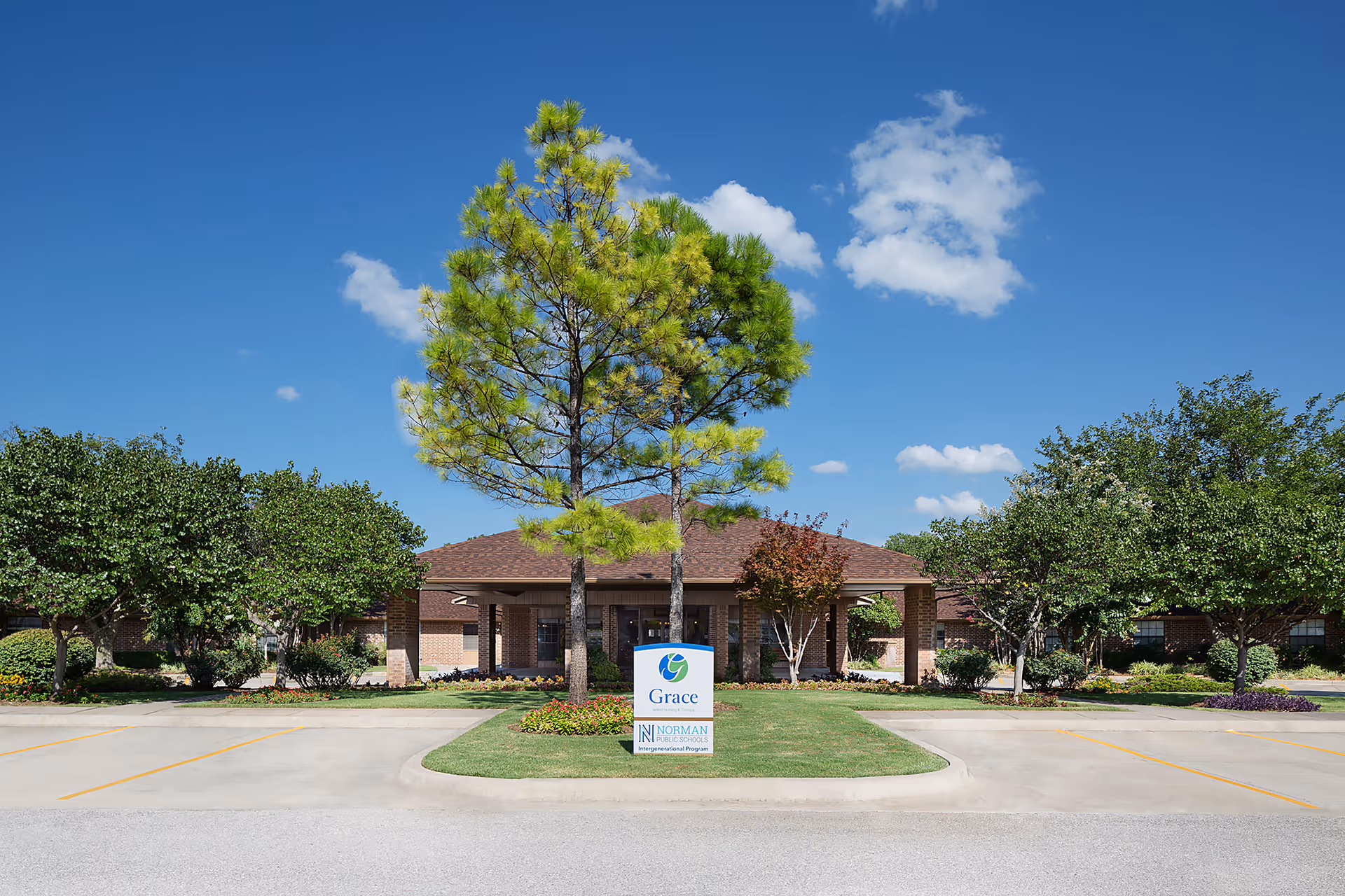 Front exterior of Grace Skilled Nursing & Therapy building with a central driveway, landscaped lawn, trees, and a sign.