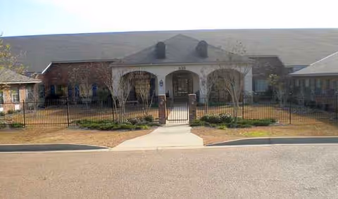 Single-story senior living facility with a gated front entrance and landscaped walkway.