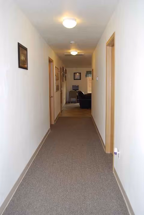 Long hallway in Regina Adult Foster Home with doors on both sides and living room visible.