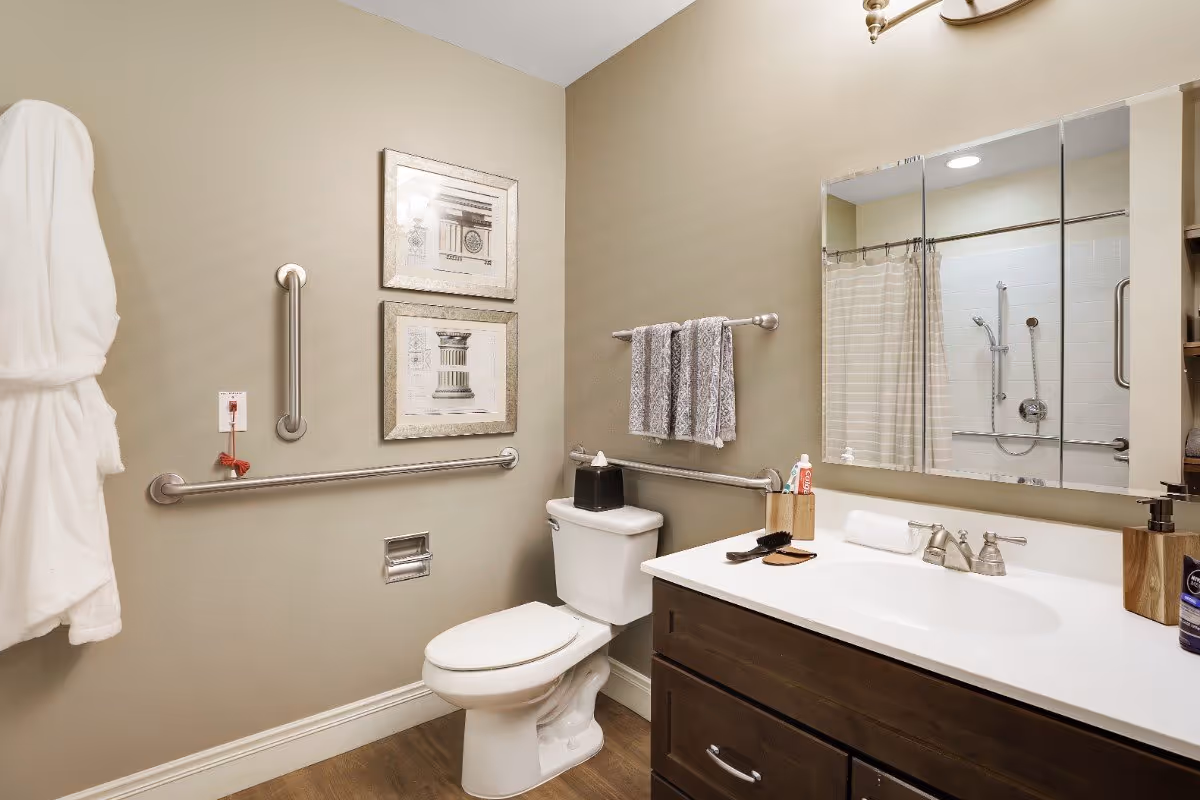 Accessible bathroom with a toilet, sink vanity and mirror, grab bars, towel rack and a shower with a curtain.