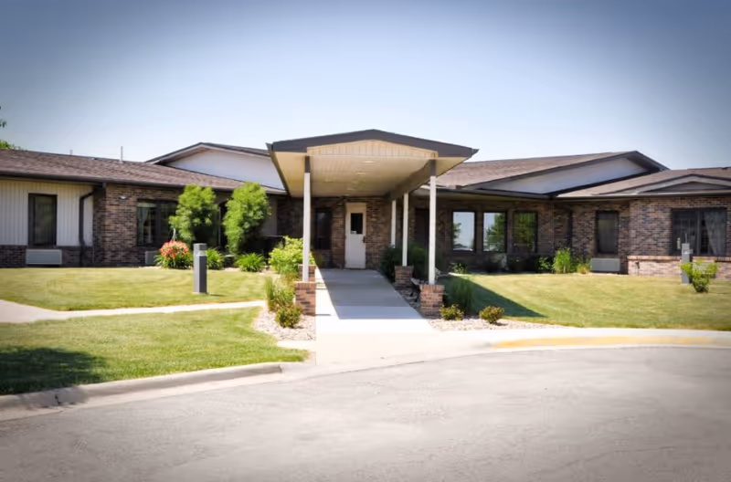 Single-story brick building with a covered entrance canopy, walkway, and manicured lawn.
