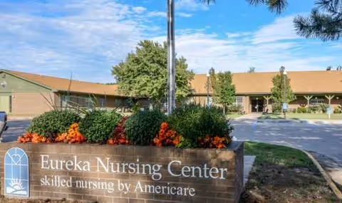 Exterior view of Eureka Nursing Center with a front sign and flowers.