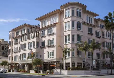 Sunrise of Beverly Hills exterior: a multi-story beige building with balconies and palm trees.